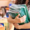 Woman carrying some books. Representing Teachers Experienced in Year 6 – Preparing for Statutory Assessment at the End of Key Stage 2
