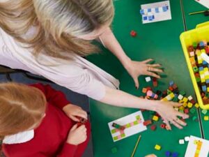 Children and their teacher using building blocks to learn maths in school. Representing What Does ‘Greater Depth’ Look Like in Maths?