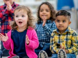 Children sat on the carpet in a classroom listening to the teacher. Representing fundamental British values and SMSC