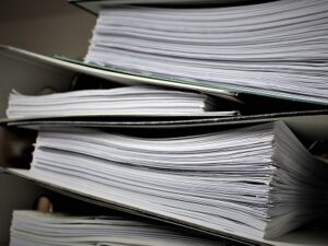 Picture of some folders, filled with files piled up. Symbolises statutory assessment and reporting.