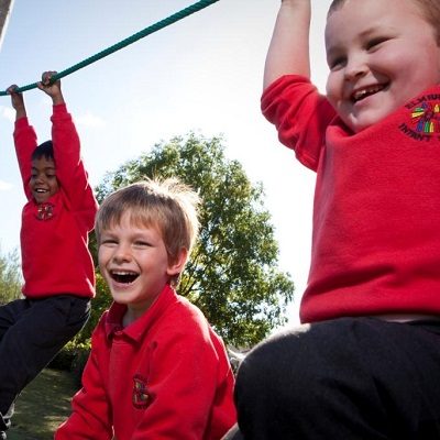 Kids playing outside on a climbing frame with ropes.