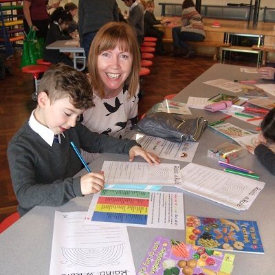 Picture of a mum and child filling out Health For Life booklets.