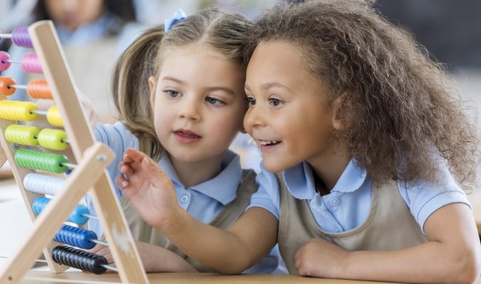 Little girls use abacus during preschool